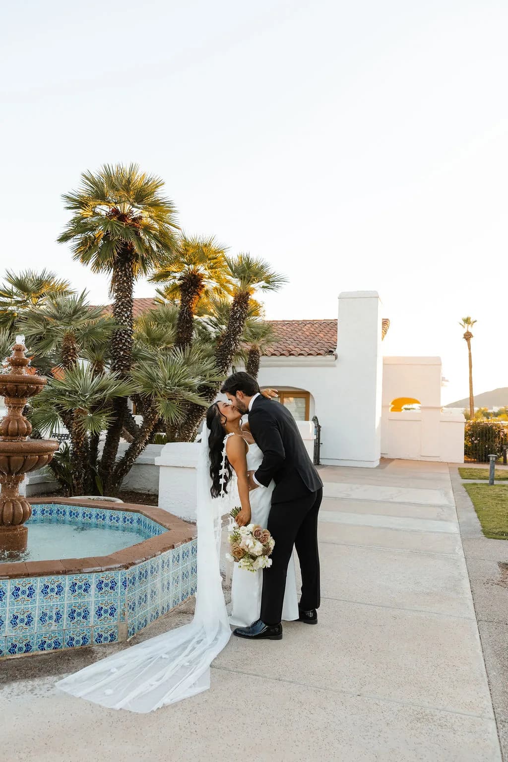 Couple beside the tiled fountain under the palms at Kimpton Miralina