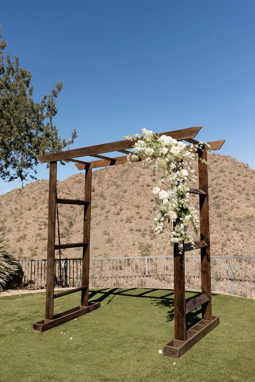 Wooden ceremony arbor with white florals against the McDowell Mountains at Adero