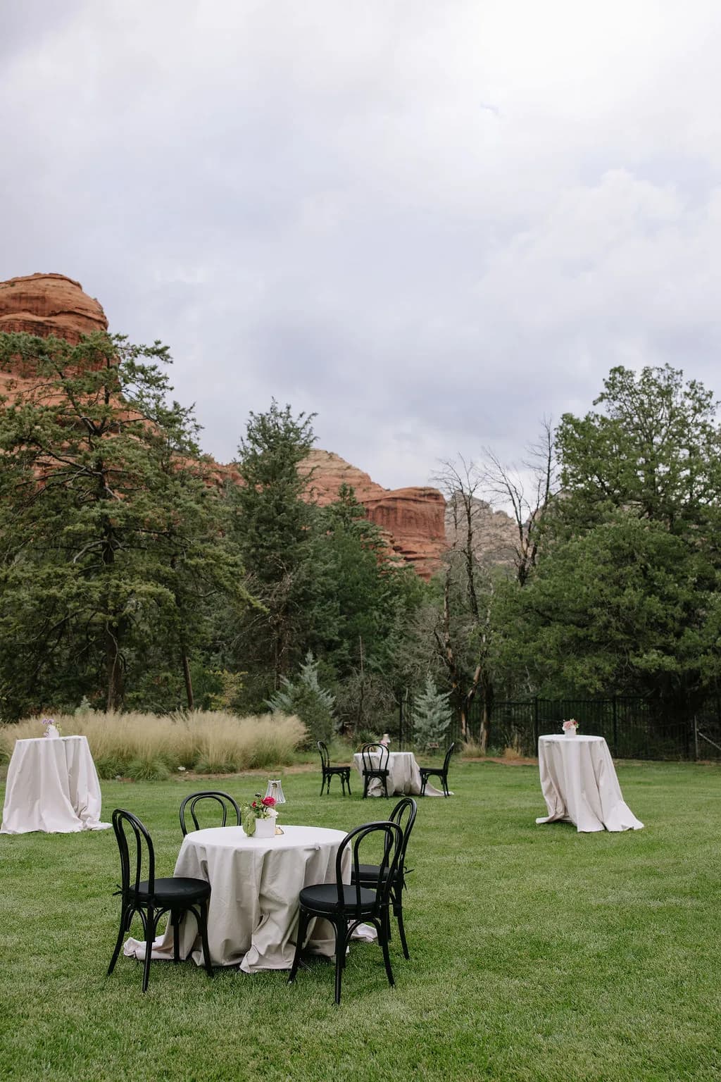 Cocktail tables on the lawn beneath red rock buttes at Enchantment Resort